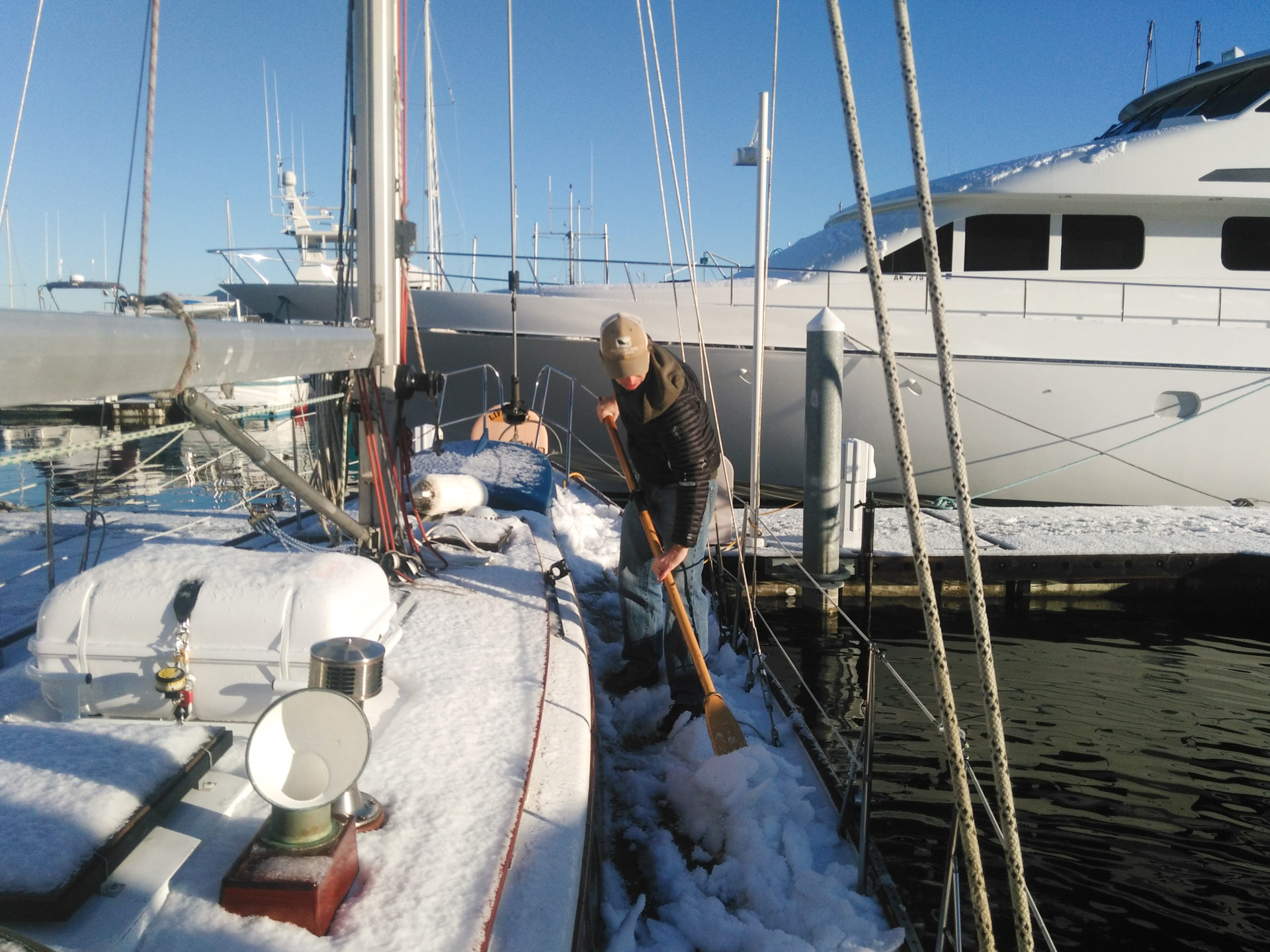 Man cleaning snow off of sail boat deck