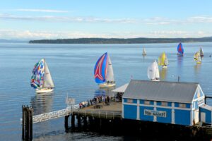 A photo of Sail boats racing by a pier