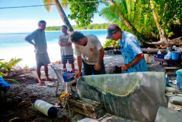 People fixing a rudder on a tropical beach