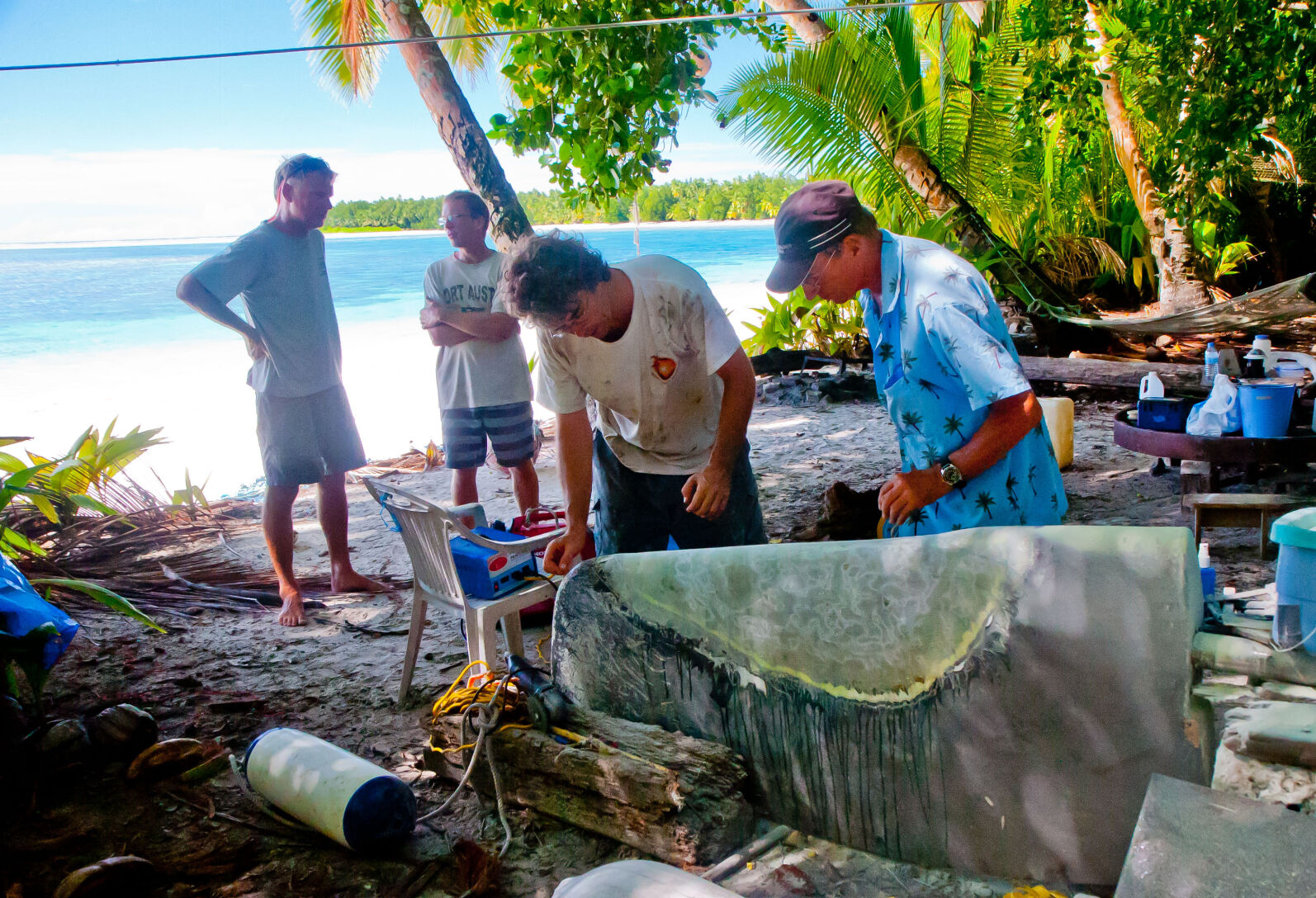 People fixing a rudder on a tropical beach