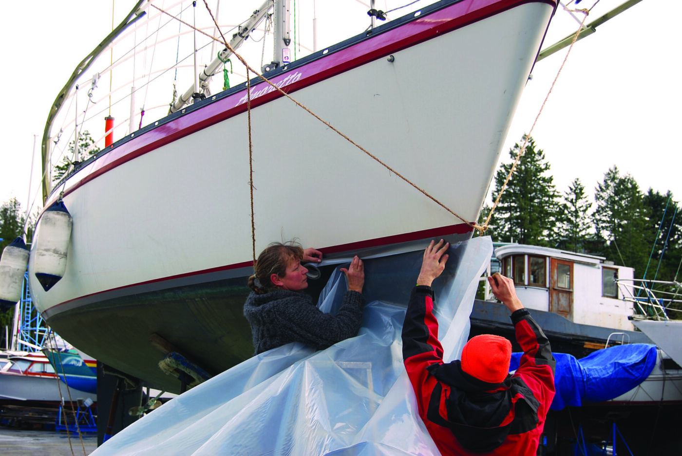 Starting at the bow, tape the 6 mil plastic to the hull to begin creating the skirt.