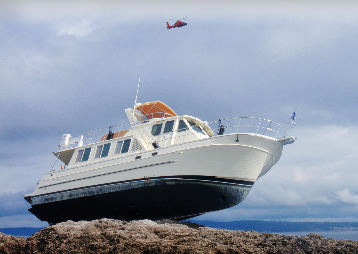 Boat atop rocks with helicopter flying above